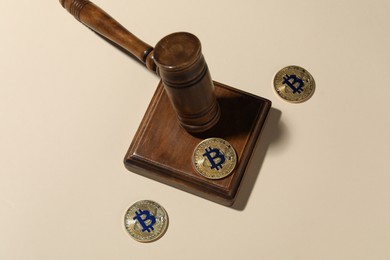 Photo of Cryptocurrency. Bitcoins and judge's gavel on beige background, above view