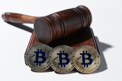 Photo of Cryptocurrency. Bitcoins and judge's gavel on white background, closeup