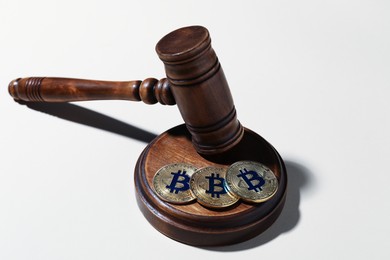 Photo of Cryptocurrency. Bitcoins and judge's gavel on white background, closeup