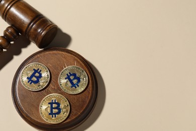 Photo of Cryptocurrency. Bitcoins and judge's gavel on beige background, flat lay. Space for text