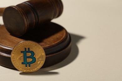 Photo of Cryptocurrency. Bitcoin and judge's gavel on beige background, closeup. Space for text