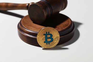 Photo of Cryptocurrency. Bitcoin and judge's gavel on white background, closeup