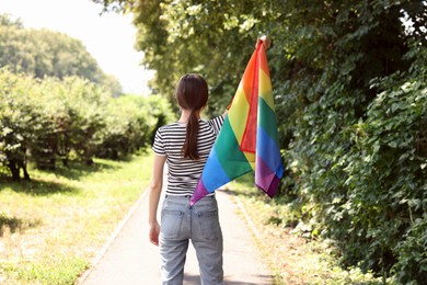 Photo of LGBT concept. Woman with rainbow flag outdoors, back view