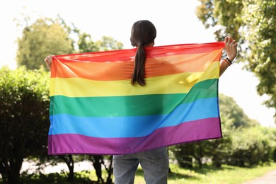 Photo of LGBT concept. Woman with rainbow flag outdoors, back view