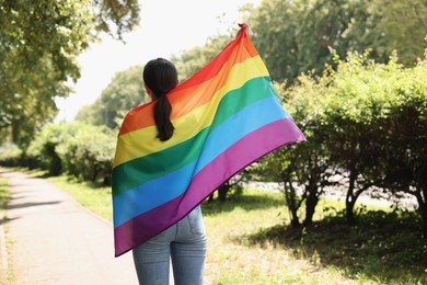 Photo of LGBT concept. Woman with rainbow flag outdoors, back view
