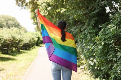 Photo of LGBT concept. Woman with rainbow flag outdoors, back view