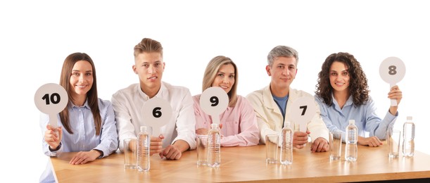 Photo of Panel of judges voting with score signs at table on white background
