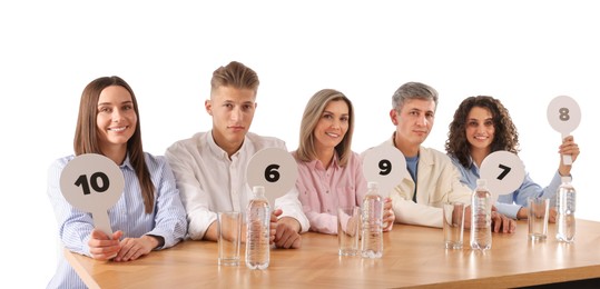 Photo of Panel of judges voting with score signs at table on white background