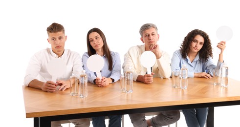 Photo of Panel of judges with blank score signs at table on white background