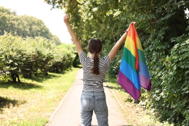 Photo of LGBT concept. Woman with rainbow flag outdoors, back view