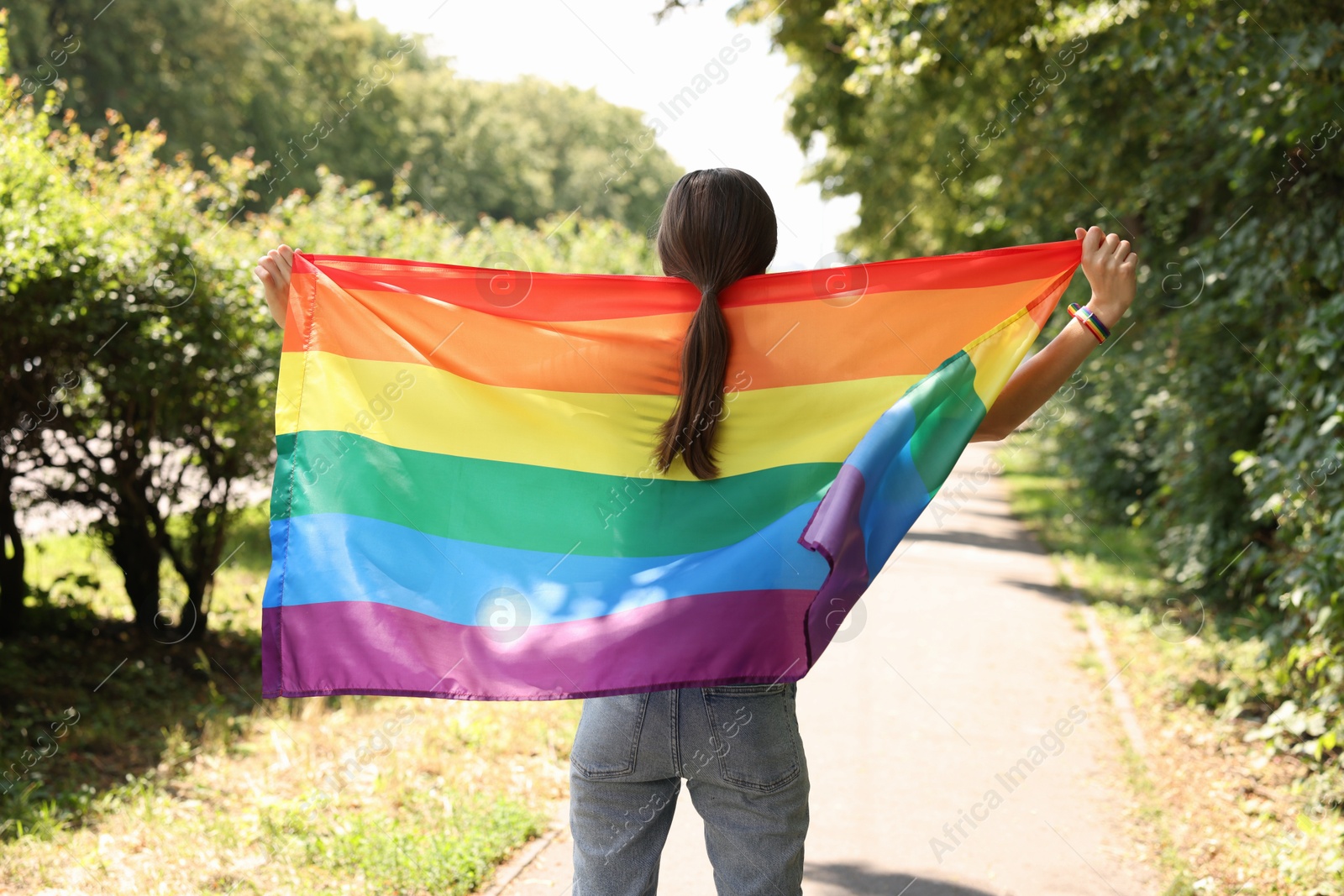 LGBT concept. Woman with rainbow flag outdoors, back view Photo of LGBT concept. Woman with rainbow flag outdoors, back view
