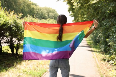 Photo of LGBT concept. Woman with rainbow flag outdoors, back view