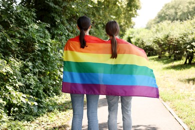 Photo of LGBT concept. Women with rainbow flag outdoors, back view