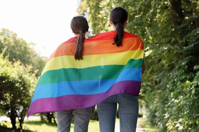 Photo of LGBT concept. Women with rainbow flag outdoors, back view