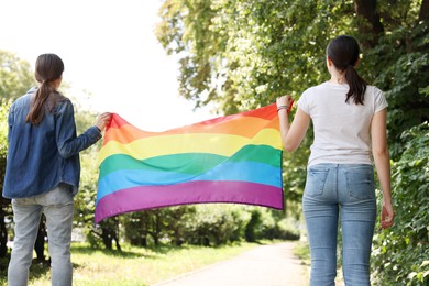 Photo of LGBT concept. Women with rainbow flag outdoors, back view