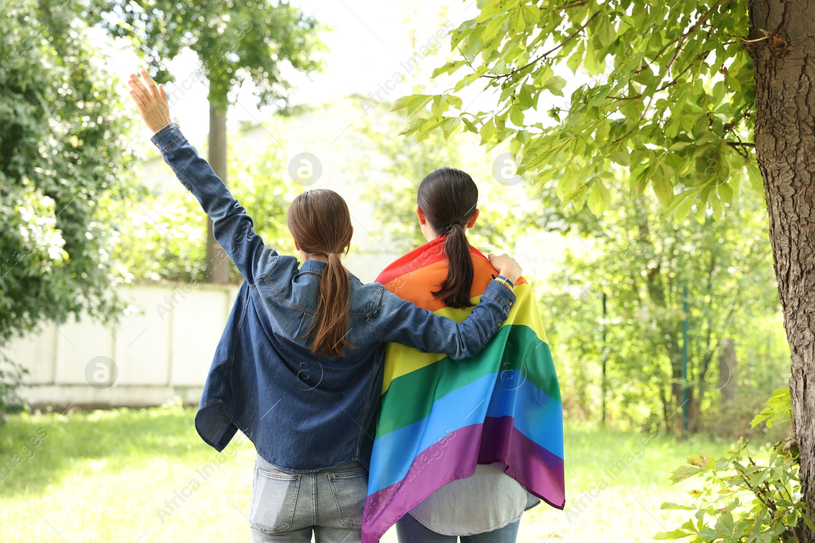 LGBT concept. Women with rainbow flag outdoors, back view Photo of LGBT concept. Women with rainbow flag outdoors, back view