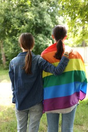 Photo of LGBT concept. Women with rainbow flag outdoors, back view