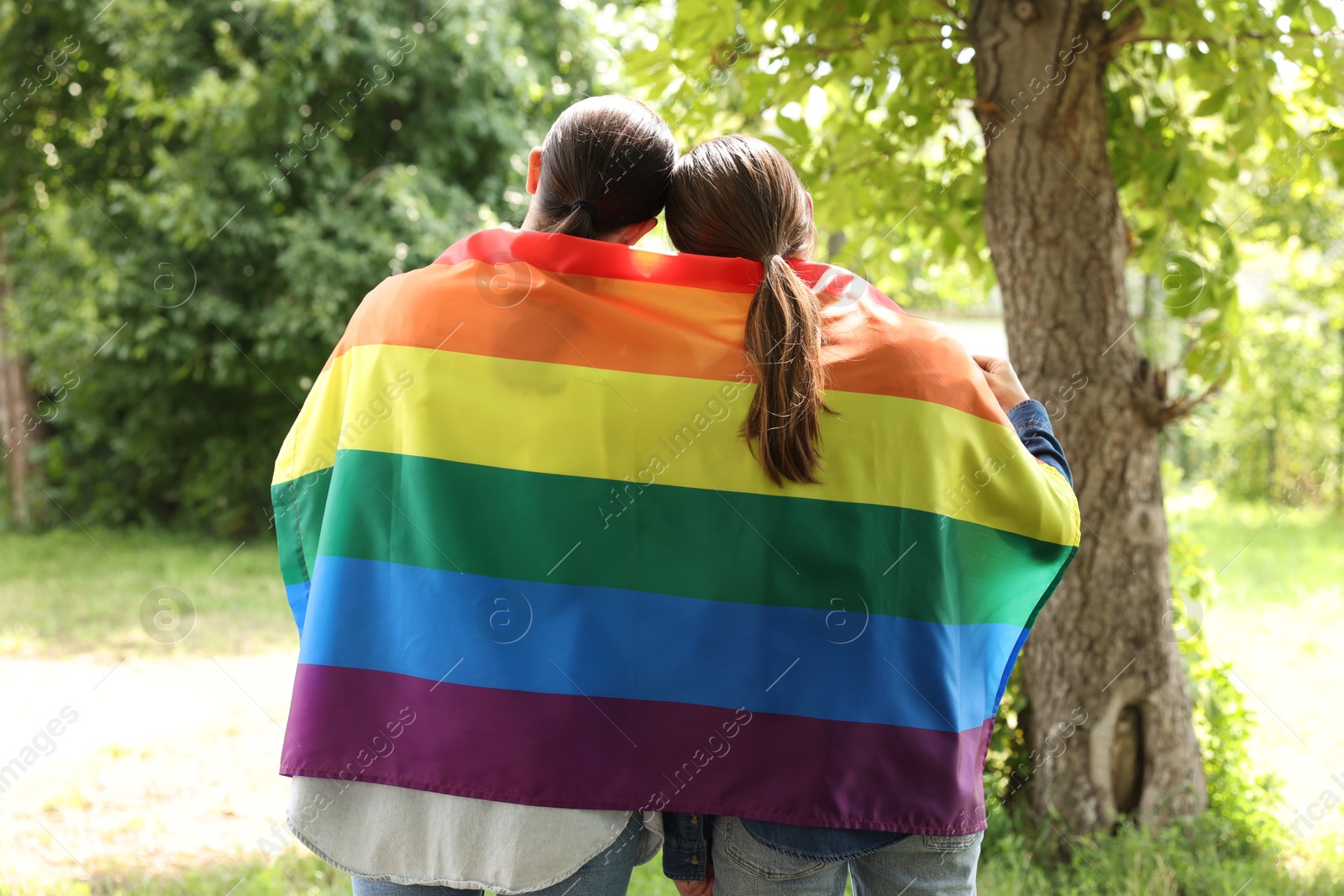 LGBT concept. Women with rainbow flag outdoors, back view Photo of LGBT concept. Women with rainbow flag outdoors, back view