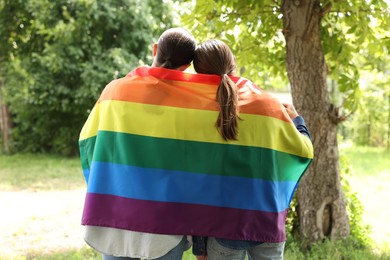 Photo of LGBT concept. Women with rainbow flag outdoors, back view