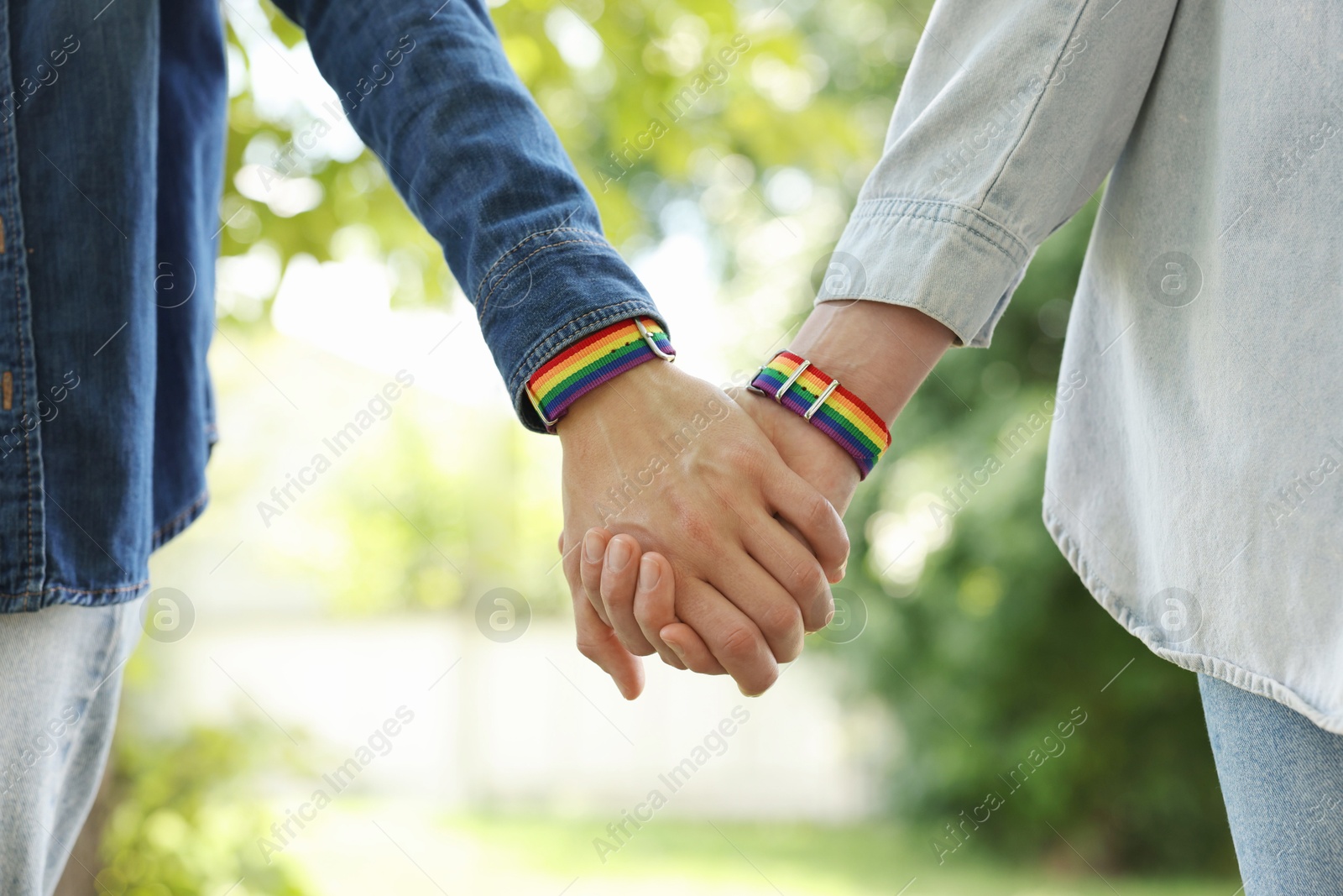 LGBT concept. Women in rainbow wristbands holding hands outdoors, closeup Photo of LGBT concept. Women in rainbow wristbands holding hands outdoors, closeup