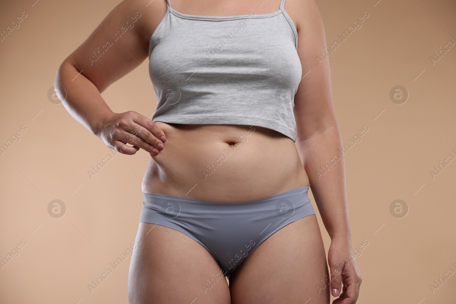 Liposuction. Woman in underwear touching her belly on beige background, closeup Photo of Liposuction. Woman in underwear touching her belly on beige background, closeup