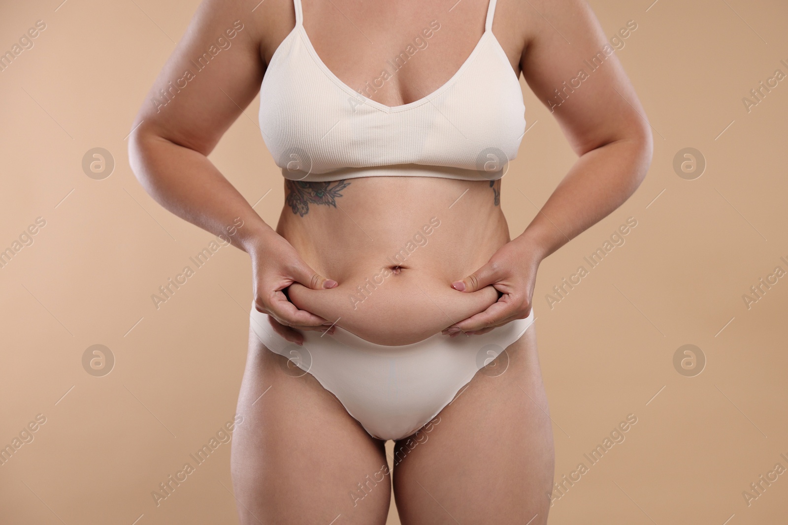 Liposuction. Woman in underwear touching her belly on beige background, closeup Photo of Liposuction. Woman in underwear touching her belly on beige background, closeup