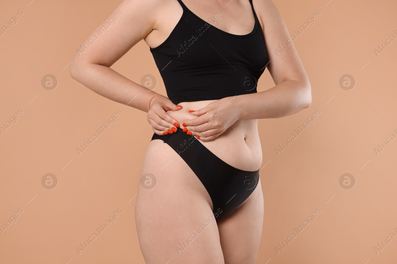 Liposuction. Woman in underwear touching her side on beige background, closeup Photo of Liposuction. Woman in underwear touching her side on beige background, closeup