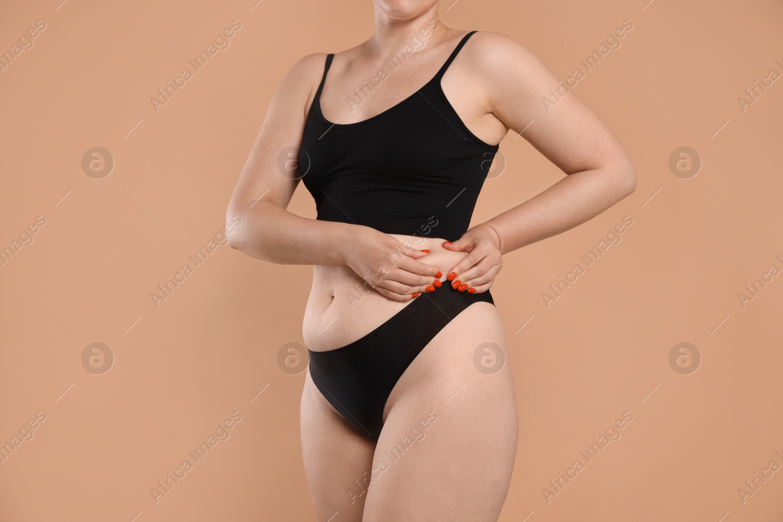 Liposuction. Woman in underwear touching her side on beige background, closeup Photo of Liposuction. Woman in underwear touching her side on beige background, closeup