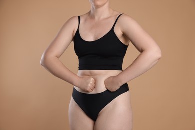 Photo of Liposuction. Woman in underwear touching her belly on beige background, closeup