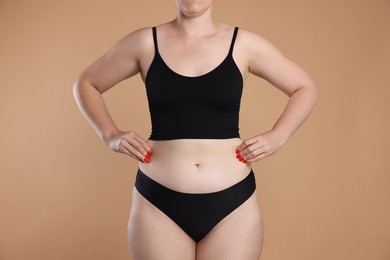 Photo of Liposuction. Woman in underwear touching her belly on beige background, closeup