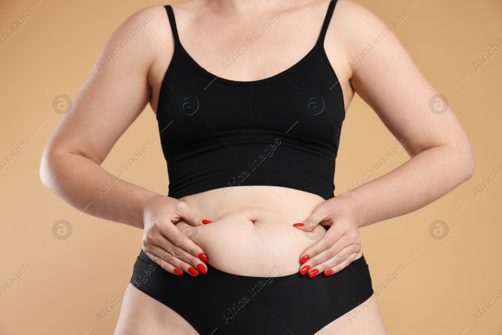 Photo of Liposuction. Woman in underwear touching her belly on beige background, closeup
