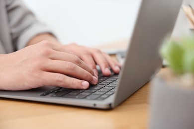 Photo of Copywriter using laptop at wooden table indoors, closeup
