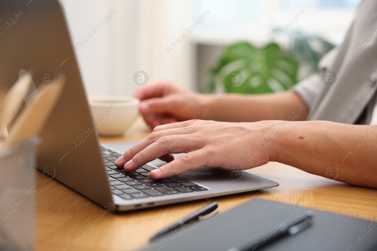 Copywriter using laptop at wooden table indoors, closeup Photo of Copywriter using laptop at wooden table indoors, closeup