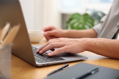 Photo of Copywriter using laptop at wooden table indoors, closeup