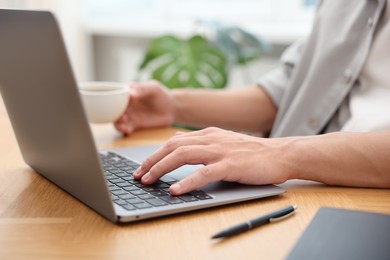 Photo of Copywriter using laptop at wooden table indoors, closeup