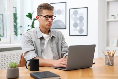 Photo of Copywriter using laptop at wooden table indoors