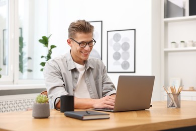 Photo of Copywriter using laptop at wooden table indoors