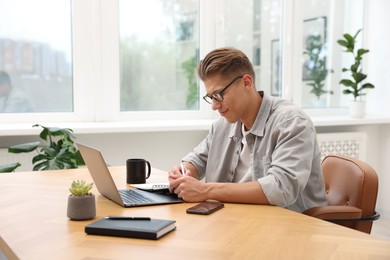Photo of Copywriter using laptop at wooden table indoors