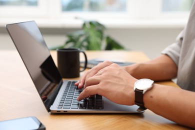 Photo of Copywriter using laptop at wooden table indoors, closeup