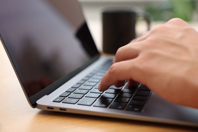 Photo of Copywriter using laptop at wooden table indoors, closeup