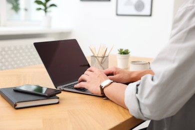 Photo of Copywriter using laptop at wooden table indoors, closeup