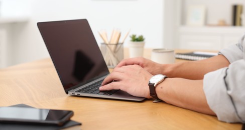 Photo of Copywriter using laptop at wooden table indoors, closeup