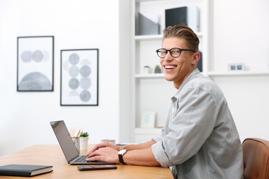 Photo of Copywriter using laptop at wooden table indoors
