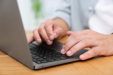 Photo of Copywriter using laptop at wooden table indoors, closeup