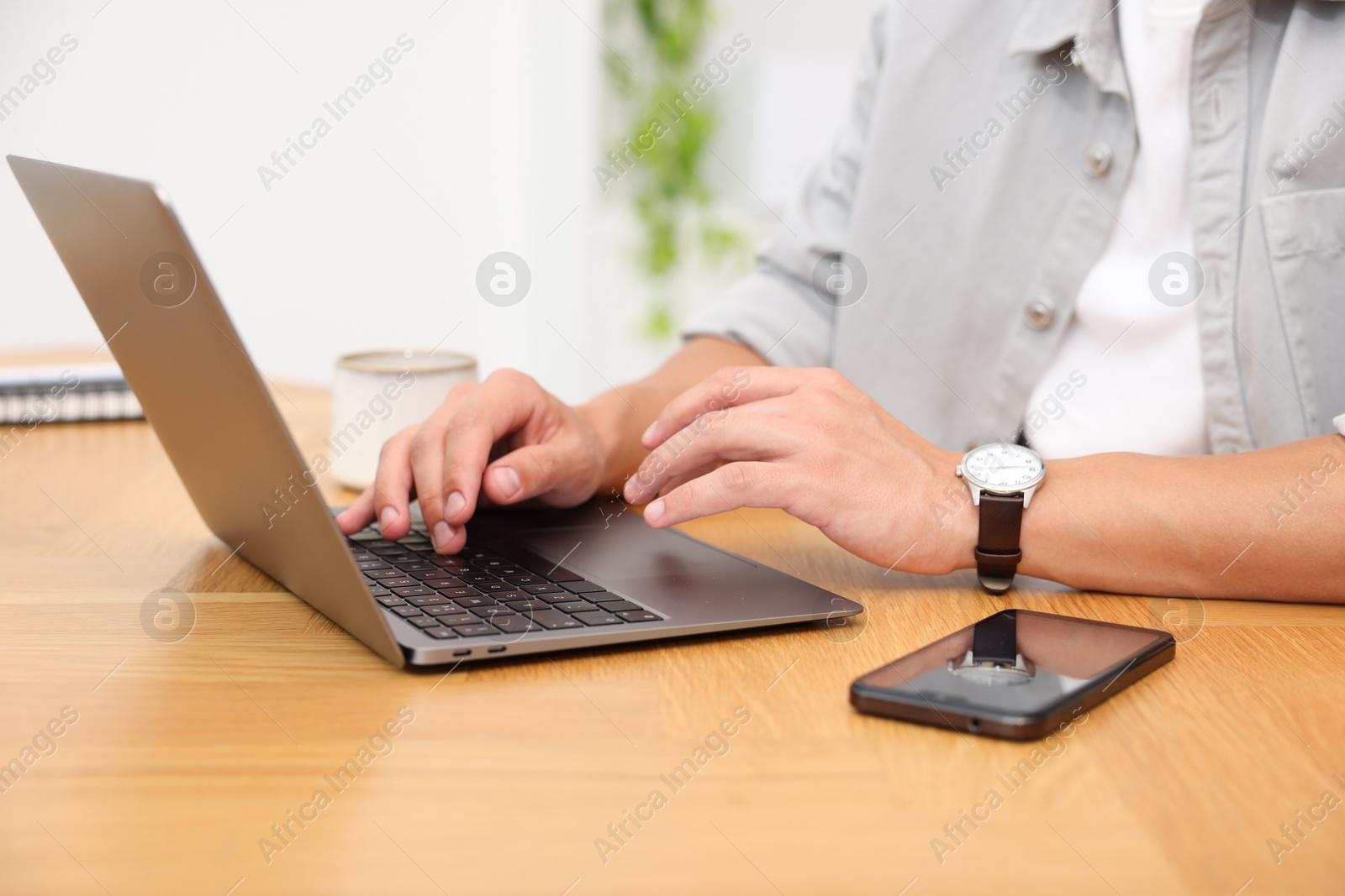 Photo of Copywriter using laptop at wooden table indoors, closeup