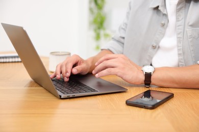 Photo of Copywriter using laptop at wooden table indoors, closeup