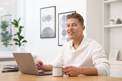 Photo of Copywriter using laptop at wooden table indoors