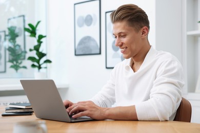 Photo of Copywriter using laptop at wooden table indoors