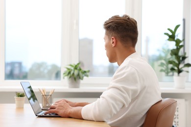 Photo of Copywriter using laptop at wooden table indoors
