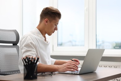 Photo of Copywriter using laptop at wooden table indoors